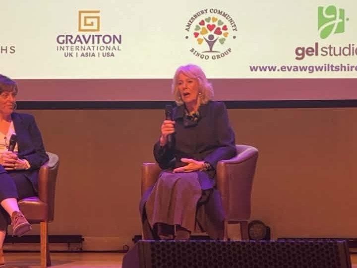 Her Majesty The Queen speaking on stage, with the summit sponsors, including Graviton International, shown on the screen above